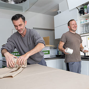 Zwei Männer verpacken Kartons in der Küche.